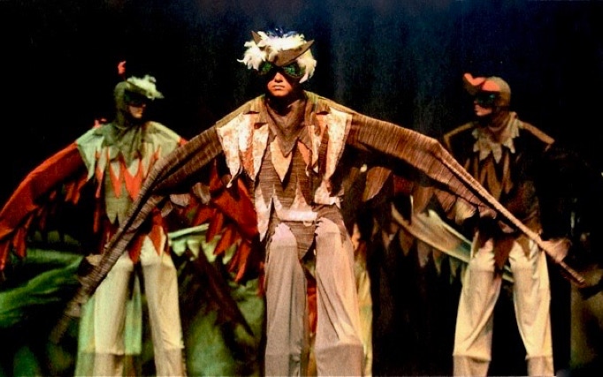 Three young actors in Birdfolk costume with masked faces and long wings.