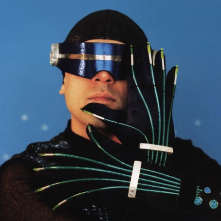 Wipe Out character in virtual reality gear, including visor and electronically wired gloves.